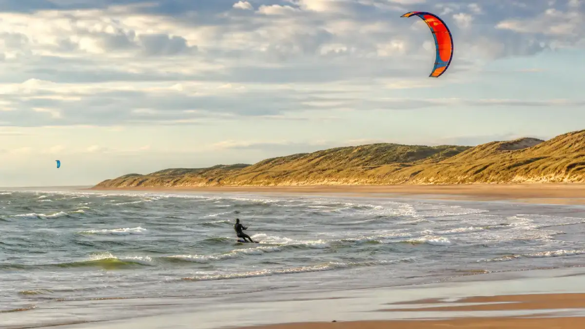 Kitesurfeur naviguant le long d’une plage bordée de dunes en Vendée